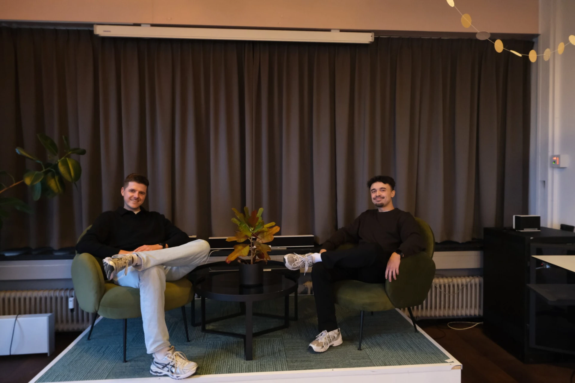 Bart en Didiet zitten in groene fauteuils naast een plant op het kantoor van druc.