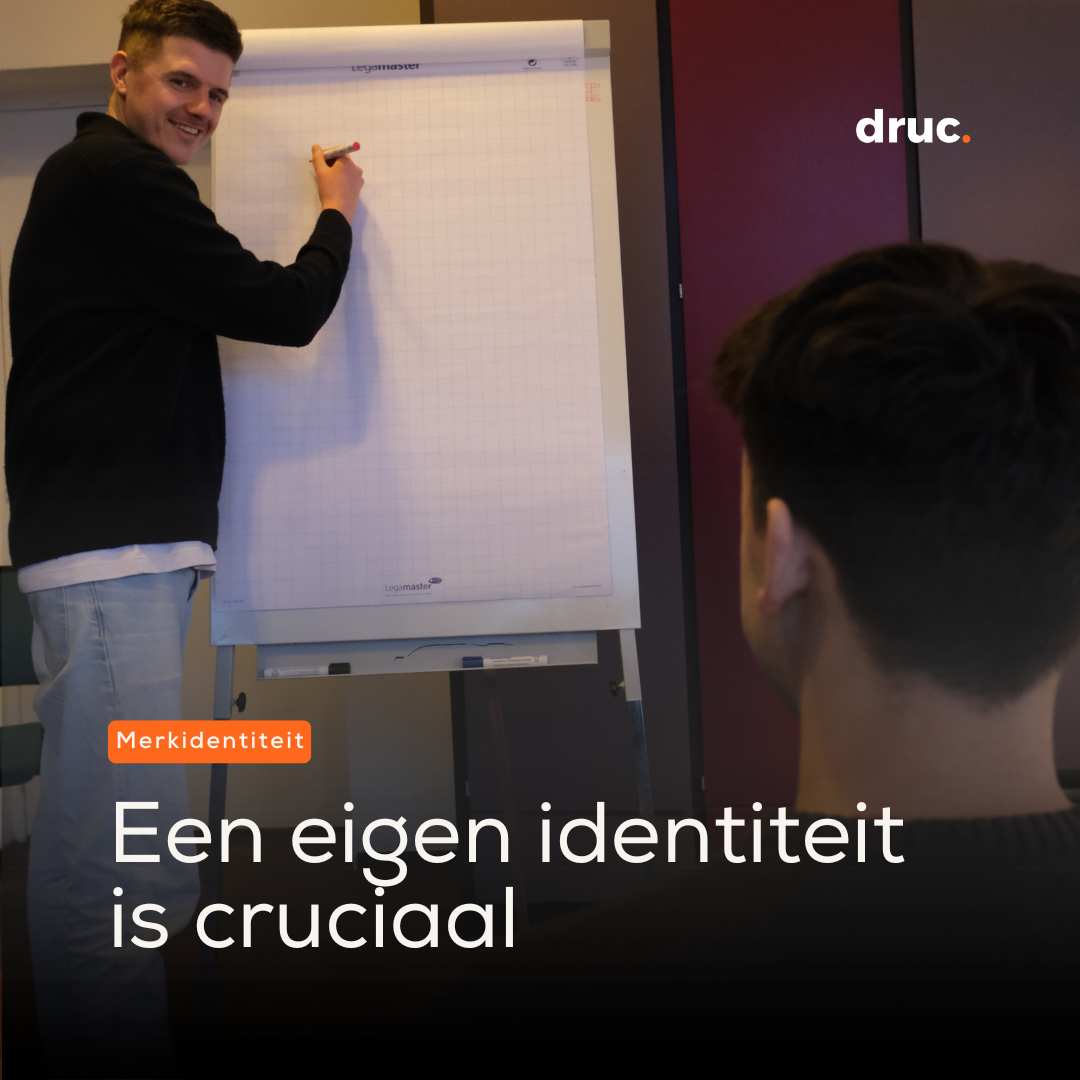 Man schrijft met een stift op een flipover terwijl een collega toekijkt.